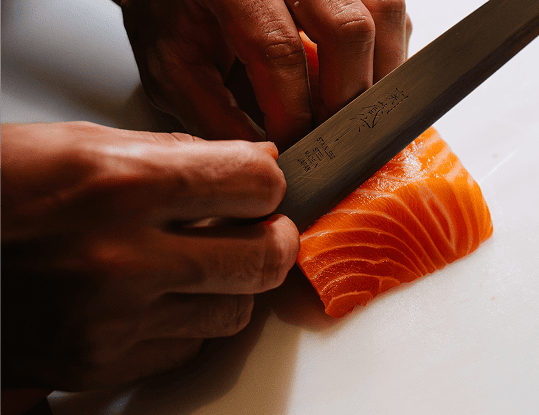 Chef executando corte preciso de sashimi